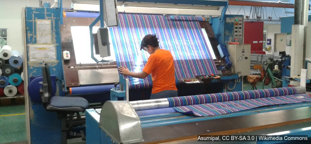 Producción de telas en planta de la industria textil Trabajadora supervisa tela estampada en maquinaria de la industria textil